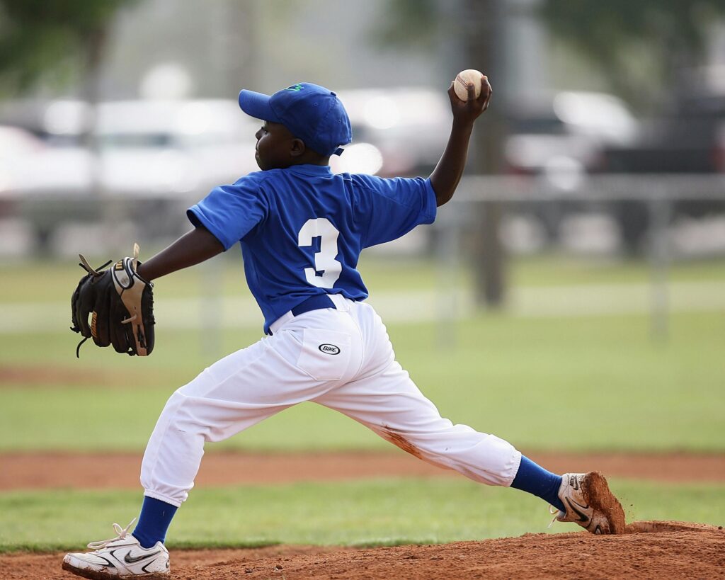 Young player pitching in a youth baseball game on a sunny day.